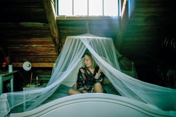 girl sitting on bed under mosquito net